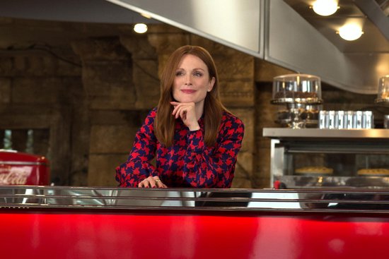 Vrouw met rood-blauw geruit shirt, zittend achter een rode balie.