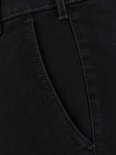 Detail van een donkerblauwe jeans, met bruine stiksels en een schuine steekzak.