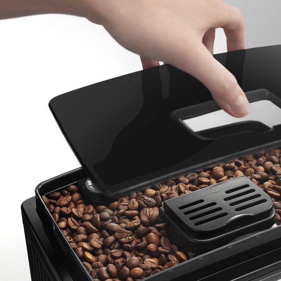 Hand opent het deksel van het bonenreservoir van de zwarte De'Longhi Magnifica S espressomachine.