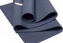 Gedetailleerde opname van een donkerblauwe, opgerolde yogamat met een textuur en een subtiele witte streep.