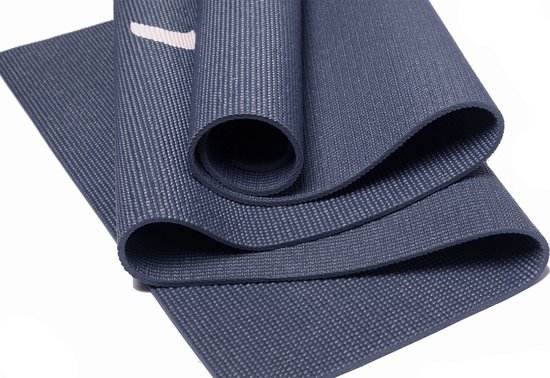 Gedetailleerde opname van een donkerblauwe, opgerolde yogamat met een textuur en een subtiele witte streep.