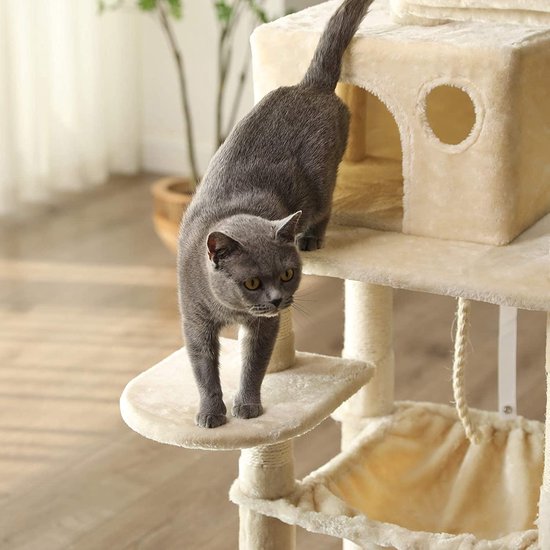Grijze kat loopt op een plateau van een beige krabpaal met huisje.