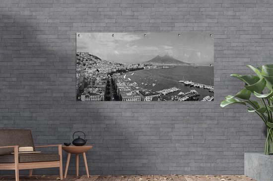 Panorama van Napels, zwart-wit, opgehangen aan een grijze bakstenen muur, naast een plant.