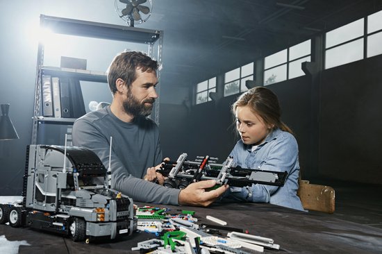 Man en meisje bouwen samen aan een LEGO Technic Mack Anthem truck. Ze kijken naar de onderdelen.