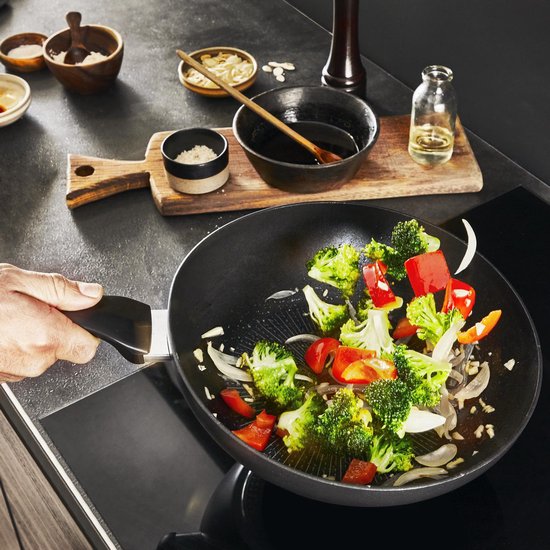 Kookscène: Hand roert broccoli, paprika en ui in een zwarte wok met rode Thermo-Spot.