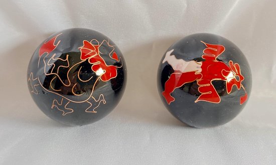 Twee glanzende, zwarte "Meridiaan"-ballen met rode en witte Draak- en Fenikspatronen.