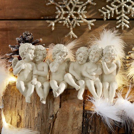 Zes witte cherubijnbeeldjes zitten op een houten stam, omringd door veren en kerstverlichting.