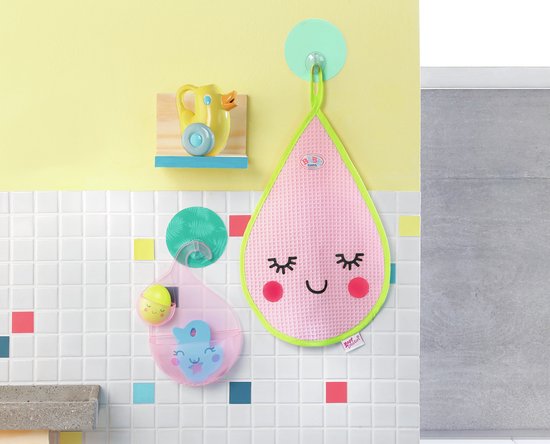 Badkamer decor met roze druppelvormige badmat aan haak. Gele badeend op plankje. Roze beker met speelgoed in, aan haak.