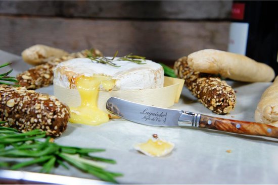 Smeltende camembert met een Laguiole botermes met olijfhouten handvat.