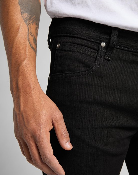 Close-up van de voorkant van een zwarte jeans met een wit T-shirt, gedetailleerde opname van de zakken.