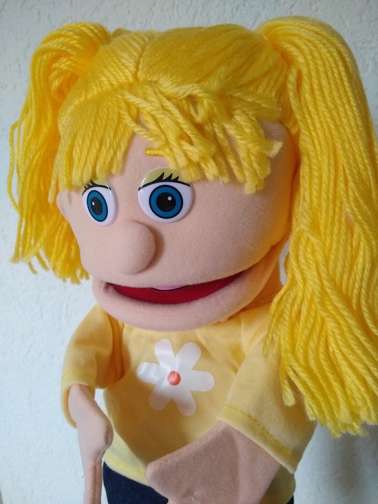 Handpop met blonde staartjes, blauwe ogen, gele trui met witte bloem en spijkerbroek.