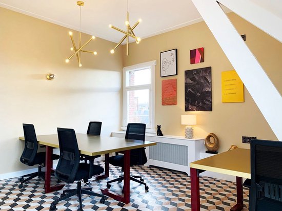 Een vergaderruimte met gouden verlichting, zwarte bureaustoelen en gekleurde kunst aan de muur.