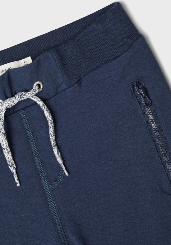 Detail van donkerblauwe joggingbroek met trekkoord en ritszak.