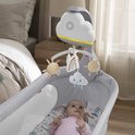 Baby in een grijs wiegje met de Fisher-Price 'Rainbow Showers' mobiel erboven, met hangende regenboogjes, wolken en zonnetjes.