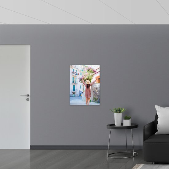 Poster Glanzend – Juichende Vrouw met Hoed bij Roze Bloemenstruik in Dorpsstraatje - 60x80 cm Foto op Posterpapier met Glanzende Afwerking