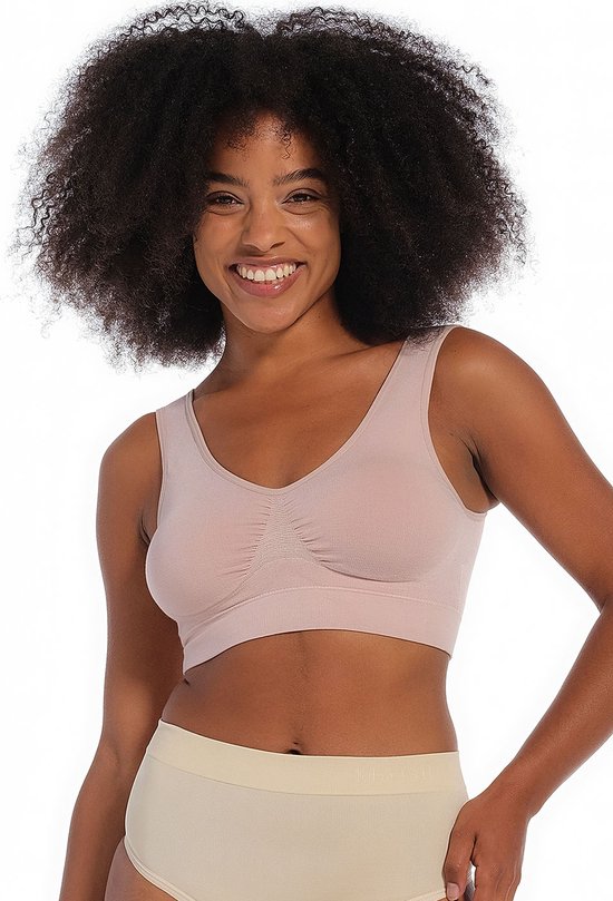 Model met krullend zwart haar draagt een roze MAGIC Bodyfashion beha.