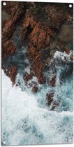 WallClassics - Tuinposter – Woesten Zee bij Rotsen - 50x100 cm Foto op Tuinposter (wanddecoratie voor buiten en binnen)
