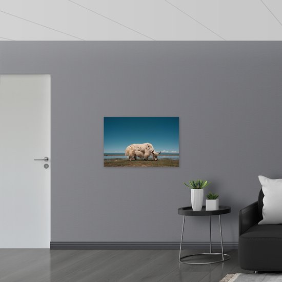 WallClassics - Muursticker - Grazende Witte Stier bij het Water - 90x60 cm Foto op Muursticker