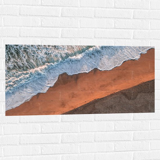 WallClassics - Muursticker - Bovenaanzicht van Golven stromend over het Strand - 100x50 cm Foto op Muursticker