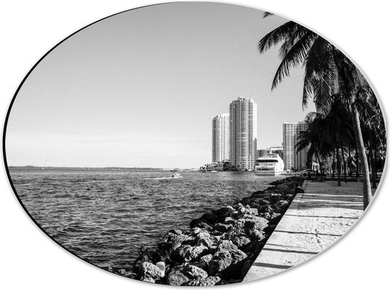 Dibond Ovaal - Palmbomen op het Strand met Uitzicht op Hoge Gebouwen Zwart/Wit - 40x30 cm Foto op Ovaal (Met Ophangsysteem)