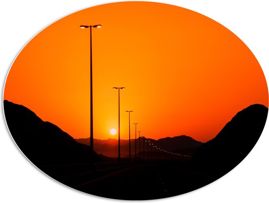 WallClassics - PVC Schuimplaat Ovaal - Zonsondergang over Weg met Lantaarnpalen tussen Bergen - 96x72 cm Foto op Ovaal (Met Ophangsysteem)