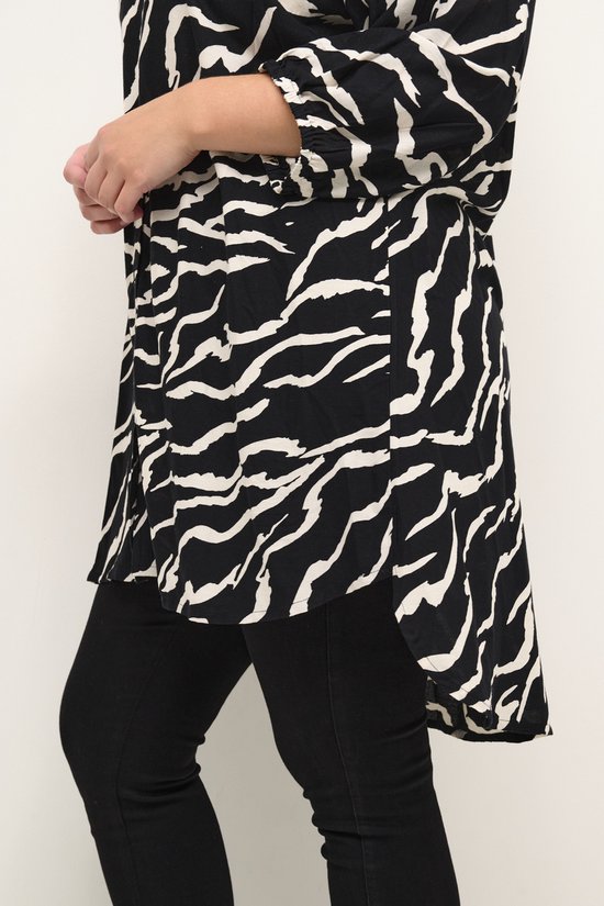 Zijenaanzicht van een zwarte blouse met witte zebraprint en driekwartmouwen, gedragen met een zwarte broek.