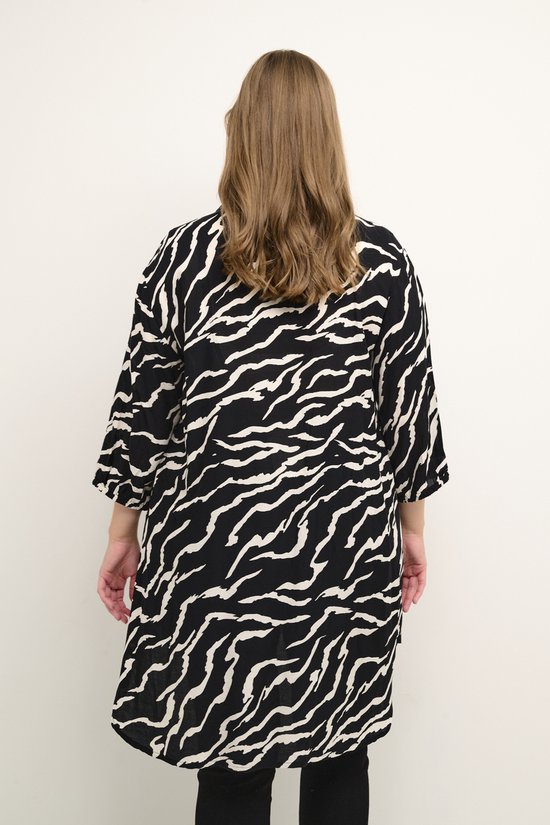 Dames met lang bruin haar in een zwarte blouse met witte zebraprint en driekwartmouwen, van achteren gezien.