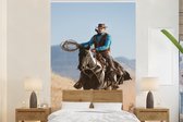 Behang - Fotobehang Een cowboy op een paard grijze hemel - Breedte 195 cm x hoogte 300 cm