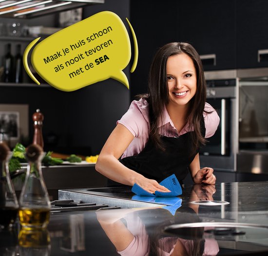 Vrolijke vrouw met schort maakt een inductiekookplaat schoon met een blauwe Sea doek.