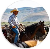 PVC Schuimplaat Muurcirkel - Cowboy op zijn Paard tussen Kudde bij Bergen - 60x60 cm Foto op Muurcirkel (met ophangsysteem)