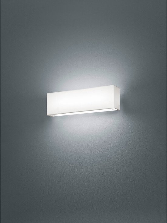Moderne, rechthoekige wandlamp met witte stoffen kap, gemonteerd op een grijze muur. Verlicht de omgeving warm.