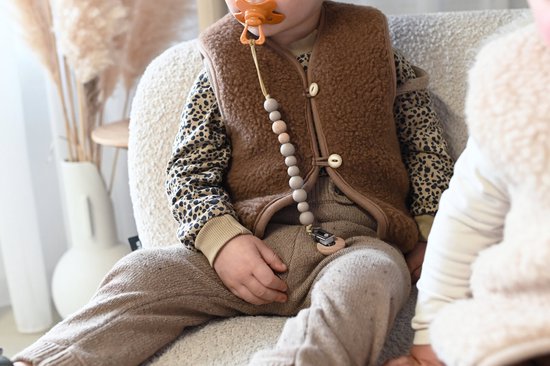 Baby zittend met bruine teddy vest en luipaardprint shirt.