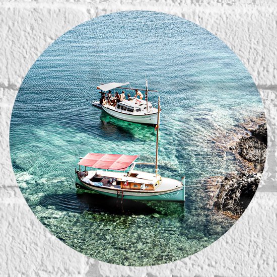 WallClassics - Muursticker Cirkel - Overdekte Vissersbootjes bij Rotsen in Blauwe Zee - 20x20 cm Foto op Muursticker