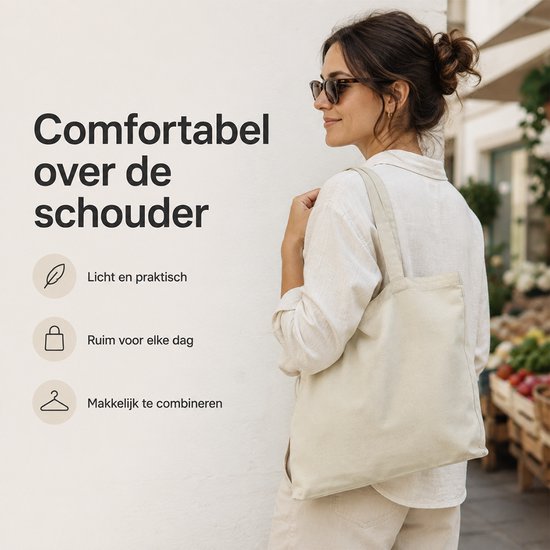 Licht beige canvas shopper met twee hengsels gedragen over de schouder door een vrouw met zonnebril.