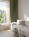 Woonkamer met een ronde bank, salontafel en een raam met beige en olijfgroene gordijnen.