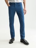 Model draagt een blauwe chino en gestreept overhemd, vooraanzicht met zwarte loafers.