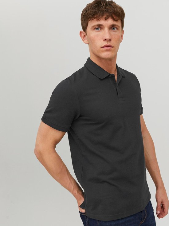 Man met donkergrijs poloshirt met korte mouwen, staand.