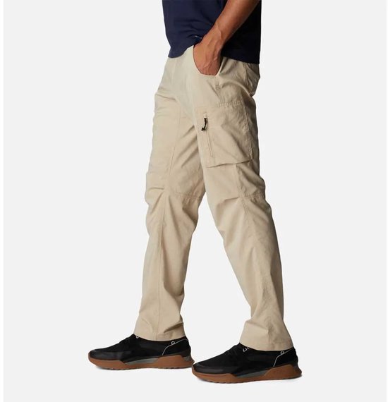 Man in beige cargo broek, lopend, zijzicht. De broek heeft een ritssluiting op de cargozak.