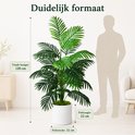 Grote groene kunstpalm van 120 cm hoog, naast een zittend figuur voor schaalindicatie.