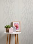Een witte ronde bijzettafel met planten en een fotolijstje met bloem staat voor een muur met verticaal bloesemdessin.
