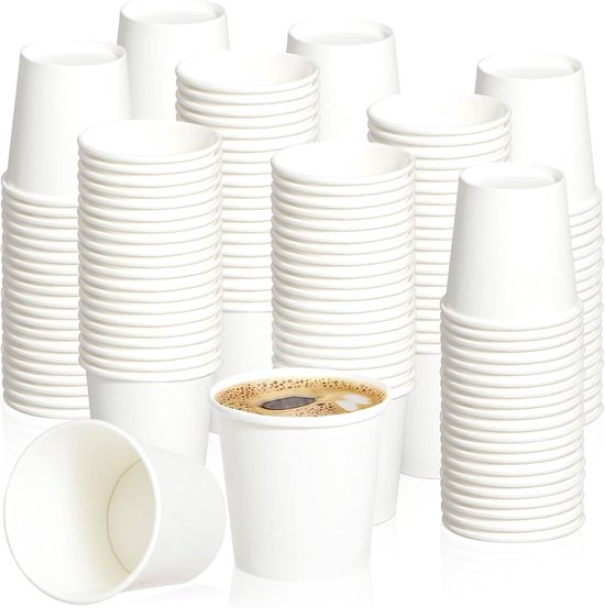 Stapel witte papieren bekers met een beker met koffie erop.