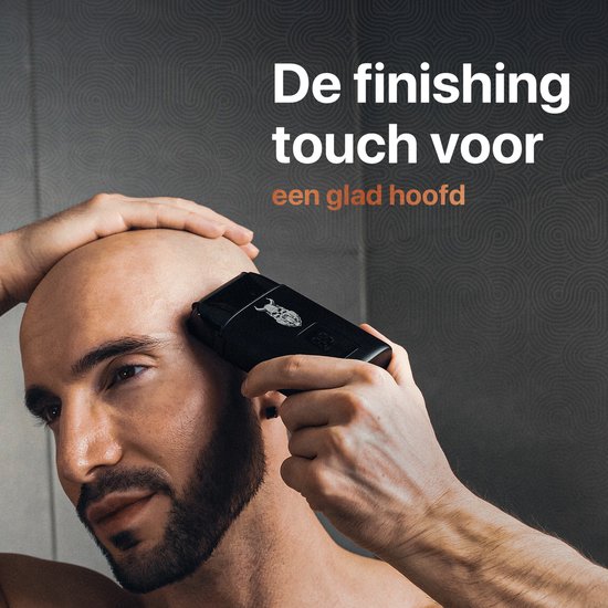 Man scheert hoofd kaal met zwart scheerapparaat met Viking-logo.