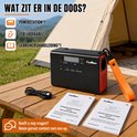 Zwarte draagbare powerstation met oranje lus, USB-kabel en handleidingen op houten tafel bij tent.