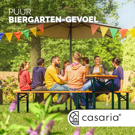 Mensen genieten aan een houten biertafel in de tuin onder vlaggetjes.