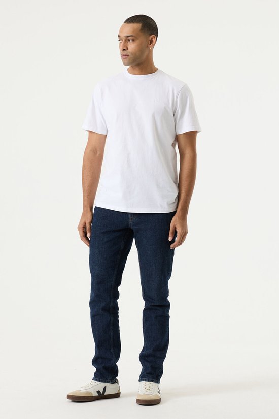 Model draagt donkerblauwe Garcia tapered fit jeans en wit T-shirt.