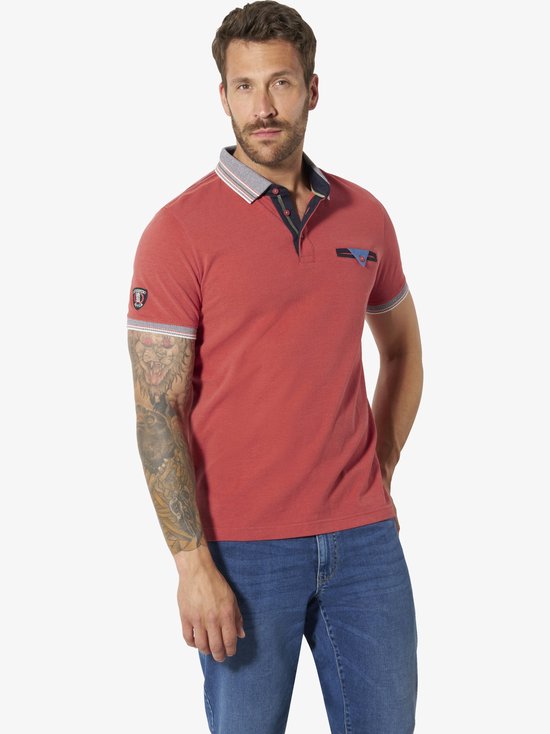 Man in een lichtrood poloshirt met opvallende kraagdetails en borstzakje, gecombineerd met een blauwe jeans.