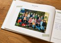 Klasfoto van veel kinderen en een paar volwassenen, staand en zittend in een bosrijke omgeving. Tekst: 'OBS Jongleren 2021-2022 Groep 1-2'.