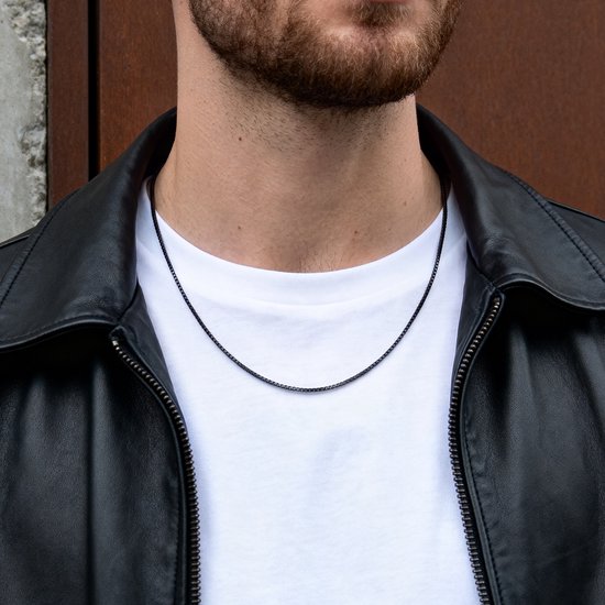 Herenketting, 1 mm breed, met vierkante Venetiaanse schakels in pistoolmetaal zwart. Gedragen over een wit T-shirt en onder een zwart leren jack.