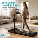 Vrouw loopt op zwarte loopband in woonkamer, kijkt op tablet, "Serie kijken terwijl je loopt".