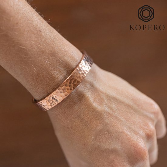 Koperen armband met gehamerde textuur om een pols gedragen. Kopero logo in de hoek.